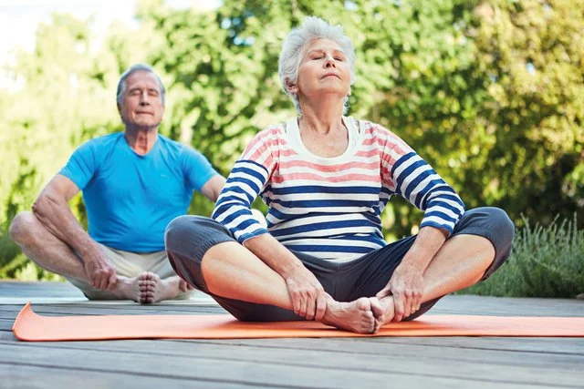 Senioren Yoga im Sitzen – Eine ältere Person macht Stuhlyoga zur Förderung von Beweglichkeit und Entspannung